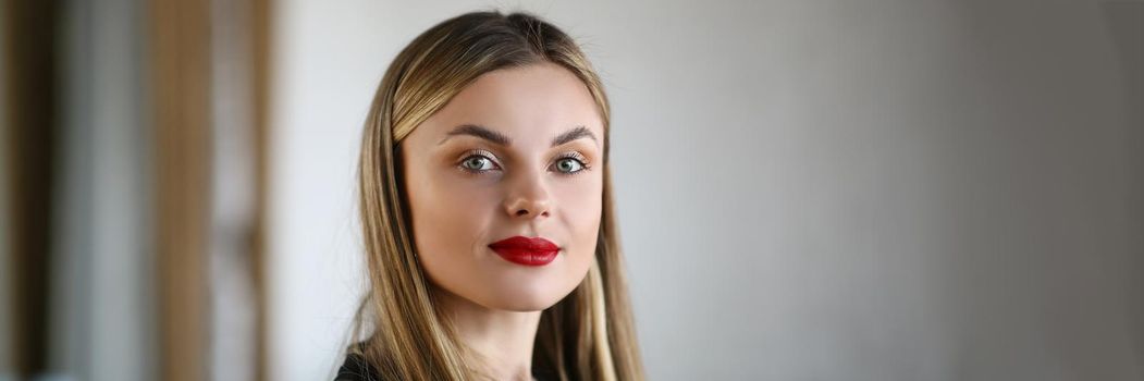 Portrait of beautiful young woman wearing bright makeup getting ready for party. Blonde woman applied red lipstick for impression. Beauty, modeling concept