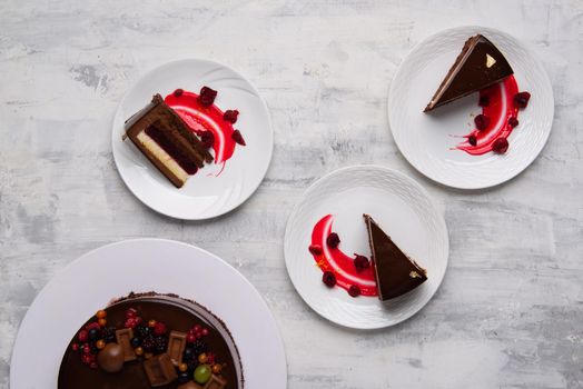 A top shot of yummy chocolate cake pieces served with a berry sauce on plates.