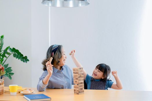 Asian portrait, grandchild granddaughter grandma grandmother and granddaughter happily join in activities to Block wood game Puzzle and enhance skills for grandchildren.