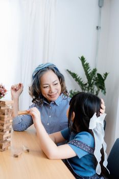 Asian portrait, grandchild granddaughter grandma grandmother and granddaughter happily join in activities to Block wood game Puzzle and enhance skills for grandchildren.