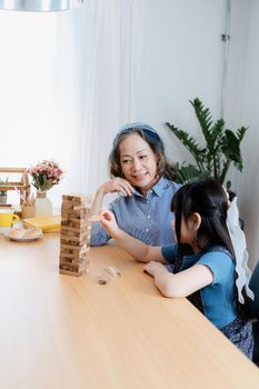 Asian portrait, grandchild granddaughter grandma grandmother and granddaughter happily join in activities to Block wood game Puzzle and enhance skills for grandchildren.