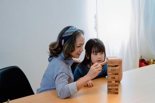 Asian portrait, grandchild granddaughter grandma grandmother and granddaughter happily join in activities to Block wood game Puzzle and enhance skills for grandchildren.