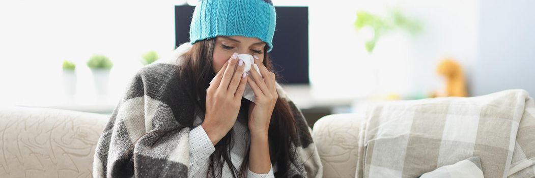 Portrait of sick woman having runny nose and use tissue covered with blanket. Unwell girl rest at home on self isolation. Covid, health, quarantine concept