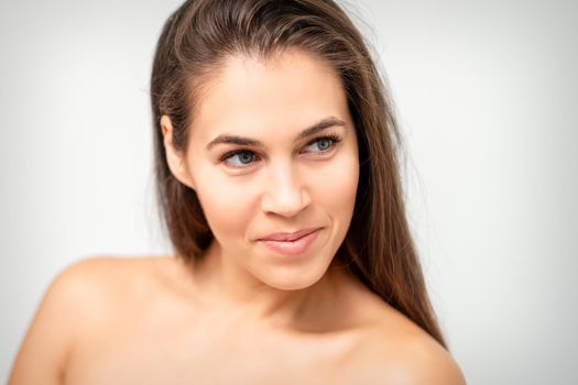 Face portrait of young caucasian woman with naked shoulders and natural make up on white background