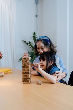 Asian portrait, grandchild granddaughter grandma grandmother and granddaughter happily join in activities to Block wood game Puzzle and enhance skills for grandchildren.