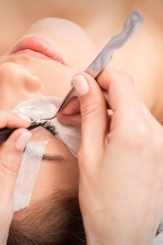 Young caucasian woman receiving eyelash extensions procedure in beauty salon