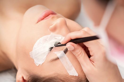 Young caucasian woman receiving eyelash extensions procedure in beauty salon