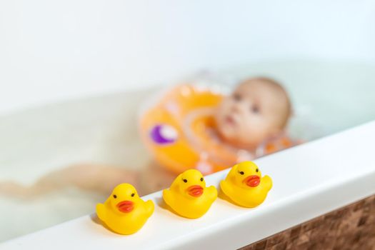 Baby is swimming in the bathroom. Selective focus. People.