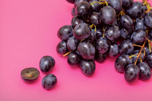 Top view bunch of ripe fresh black grape berry on pink surface
