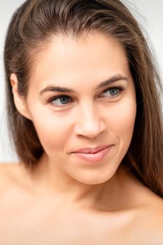 Face portrait of young caucasian woman with naked shoulders and natural make up on white background