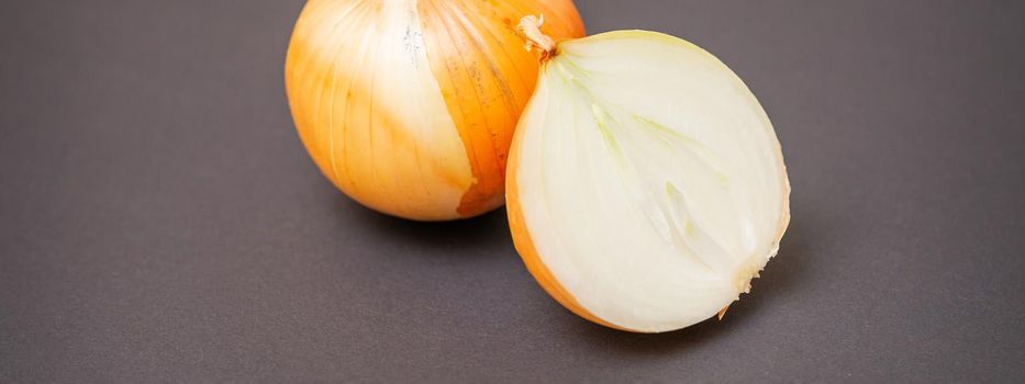Two unpeeled whole and half raw yellow onions on black surface. Flat lay. Copy space