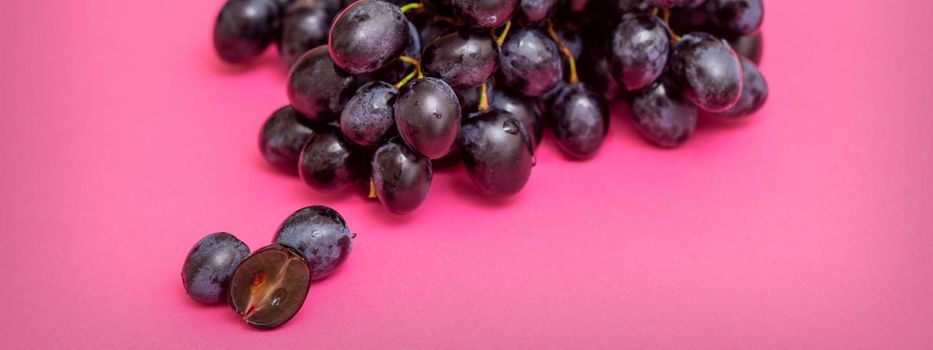 Top view bunch of ripe fresh black grape berry on pink surface