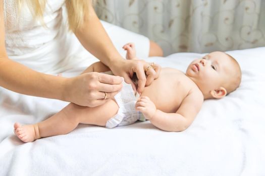 The mother changes the baby's diaper. Selective focus. People.