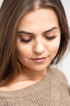 Portrait of beautiful young caucasian woman with closed eyes after eyelash extension procedure and permanent makeup