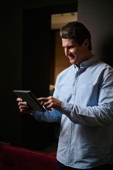 Happy confident and successful Caucasian mature male interior designer, entrepreneur working at the office using a digital tablet