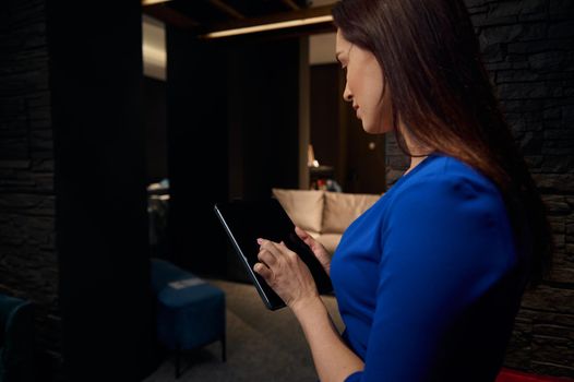 Detail: Hand of a manager on blank screen of a tablet with copy space for advertising text. Rear view of businesswoman, entrepreneur, retail assistant, interior designer using digital gadget in office