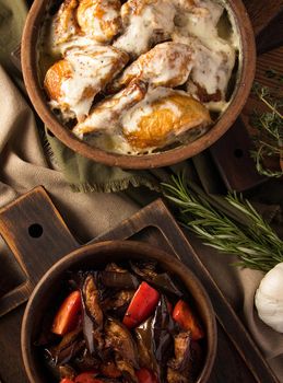 A vertical shot of a chicken covered in creamy sauce and eggplant salad