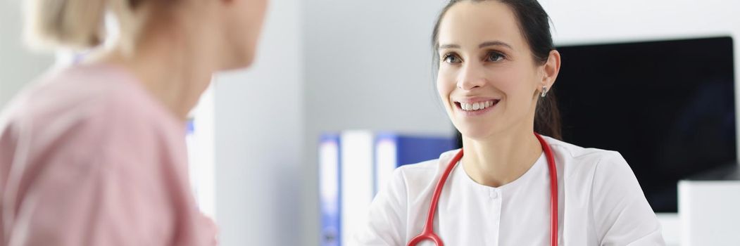 Portrait of smiling doctor measuring patients blood pressure with tonometer tool and talk. Planned checkup at family doctor. Medicine, healthcare concept