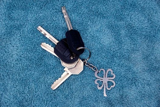 A bunch of keys from the apartment with a keychain on a blue background.