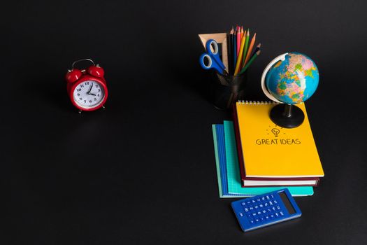 Some educational school supplies on a black background.