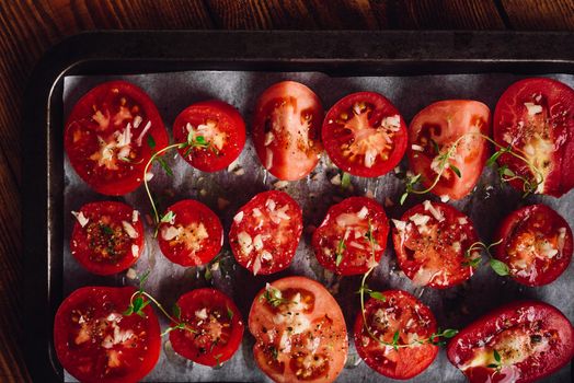 Preparation of Sun-dried Tomatoes. Halved Tomatoes with Thyme and Garlic on Baking Tray. View from Above