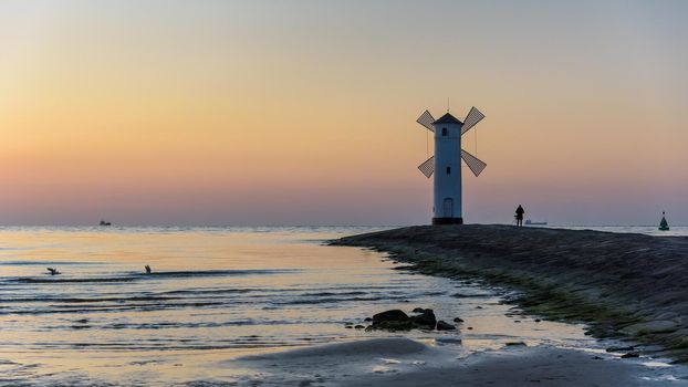Photographer takes picture of the Stawa Mlyny, a beacon in the shape of a windmill as an official symbol of Swinoujscie at dusk