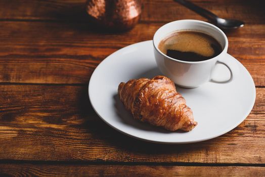 Cup of Black Coffee and Fresh Croissant on White Plate