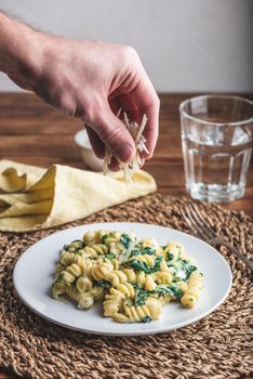 Fusilli Pasta with Spinach and Ricotta Garnished with Grated Parmesan Cheese on White Plate