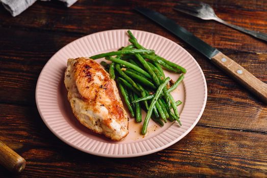 Crispy Oven-baked Chicken Breast Served on Plate with Green Beans Fried with Garlic and Thyme