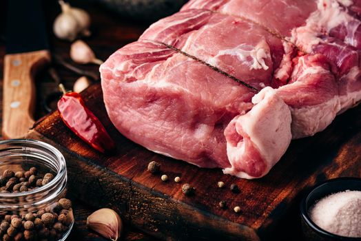 Rolled pork loin joint on cutting board with different spices