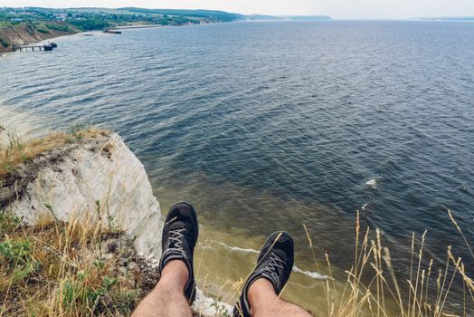 POV point of view of man sitting on the edge of cliff looking down at the river