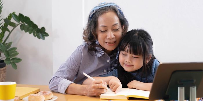 happy asian family grandmother reading to granddaughter child book at home