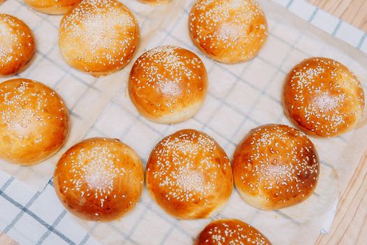Freshly baked burger buns with sesame seeds. We cook at home.