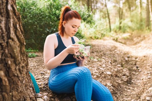 young fitness girl eating salad after training outdoors. athlete exercising outdoors. lifestyle health and wellness. outdoor public park, natural sunlight.