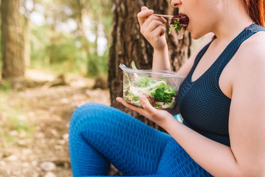 cropped shot of a young female athlete eating healthy after training. athlete exercising outdoors. lifestyle health and wellness. outdoor public park, natural sunlight.