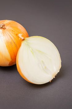 Two unpeeled whole and half raw yellow onions on black surface. Flat lay. Copy space