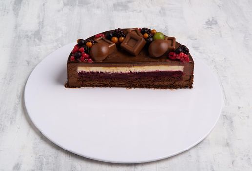 An angle shot of the half of a chocolate glaze cake decorated with berries.