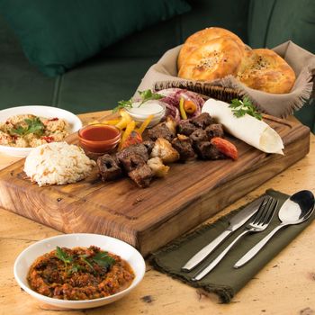 A close up shot of a meat kabab near basket of breads