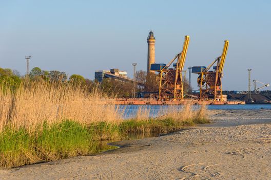 Port cranes and a lighthouse in Swinoujscie in Poland on a sunny afternoon