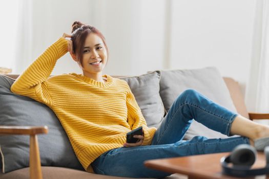 Portrait of Happy young asian woman is relaxing on comfortable couch at home. Relax concept