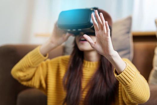 Exciting asian woman with wearable VR headset playing sport gaming online in living room at home