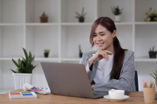 Beautiful smiling young graphic designer sitting at desk in office and working.