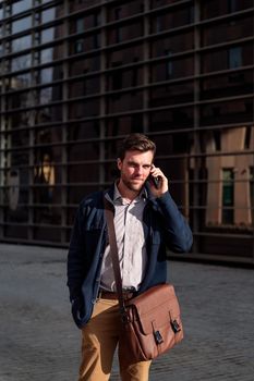 young businessman walking by the offices in the financial district talking on the telephone, concept of entrepreneurship and business, copy space for text