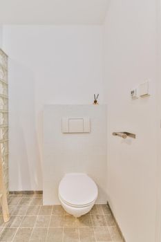 Modern toilet mounted on a white wall under a button under a shelf with a diffuser