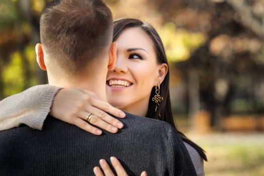 Portrait of a young Asian woman hugging her caucasian man back view. interracial marriage.