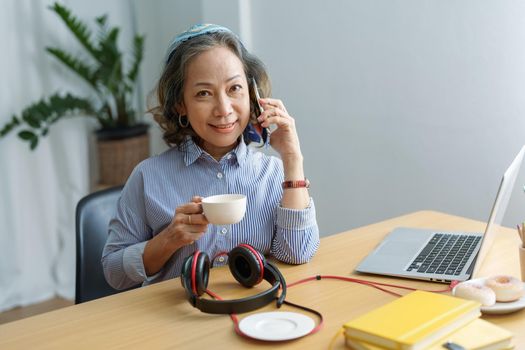 Portrait of an elderly woman talking to a friend on the phone during a coffee break.