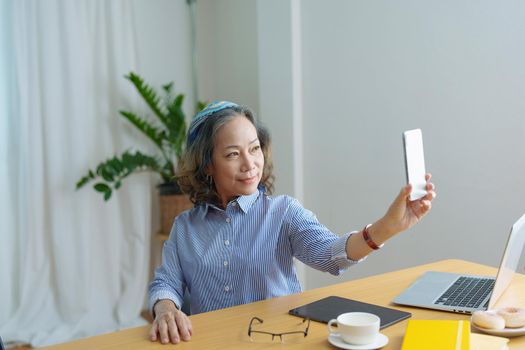 Portrait of an elderly woman talking to a friend on the phone during a coffee break.