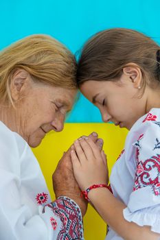 Ukrainian grandmother and granddaughter in vyshyvanka. pray, selective focus. Kid.