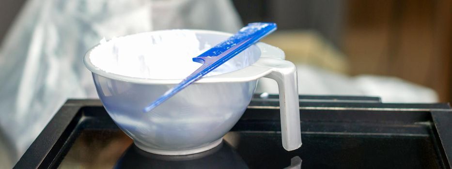 White hair dye in container on the special table in hair salon