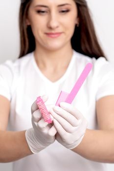 Manicure tools in hands of young female manicure master on white background. Selective focus